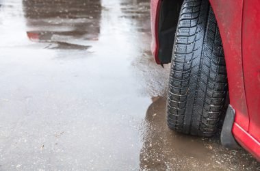 driving car in rain - view of vehicle wheel on wet road